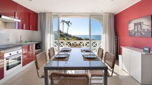 Une cuisine moderne avec un coin repas, de grandes fenêtres et une vue sur la mer.