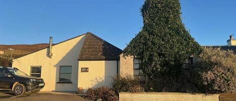A small building with a sloped roof, a chimney, and a window.