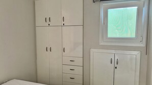 Een slaapkamer met een bed, een kledingkast, een bureau en een raam met gordijnen.