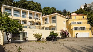 A multi-story building with balconies, a car parked in front, and a gravel driveway. - Silver 2 Apartment (Cannes)