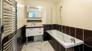 A modern bathroom with a bathtub, a mirror, a towel rack, and a sink. - Silver 2 Apartment (Cannes)