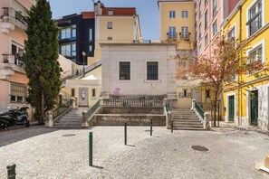 A cobblestone courtyard with a staircase leading to a building with a balcony.