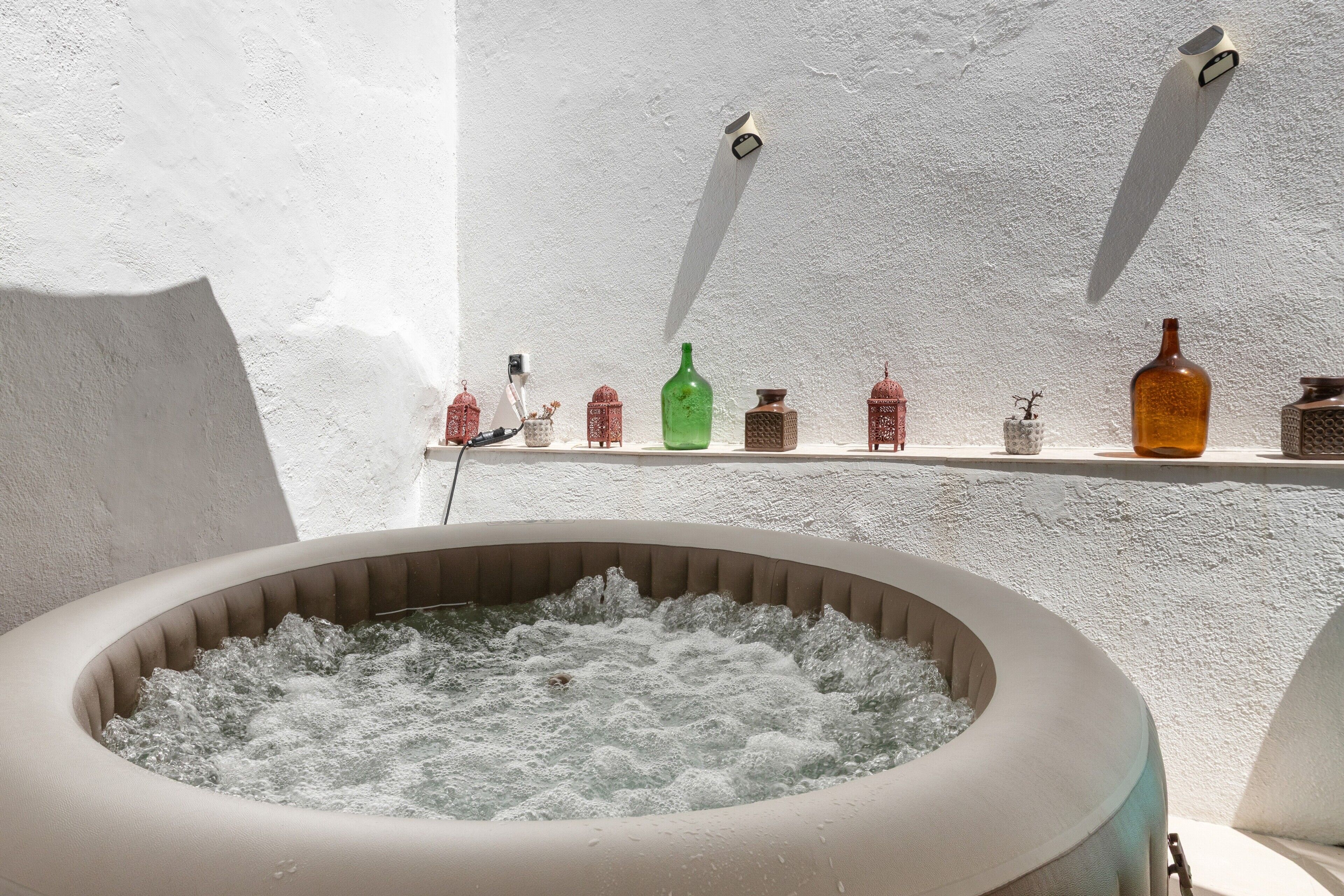 A spa area with a hot tub surrounded by shelves holding various bottles and containers.