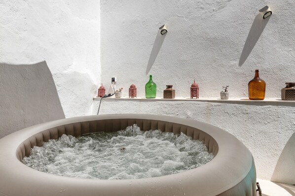 A spa area with a hot tub surrounded by shelves holding various bottles and containers.