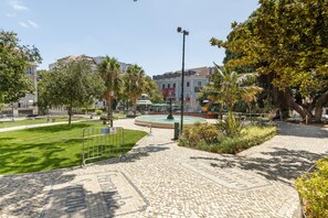 A paved plaza with a fountain, surrounded by trees and buildings.