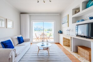 Ein Wohnzimmer mit einer Couch, einem Tisch, einem Fernseher und einem Kamin.