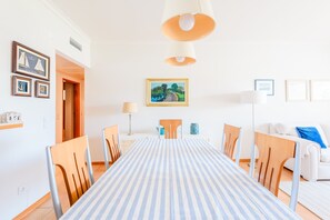 Ein Essbereich mit gestreifter Tischdecke, Holzkästen, einem Bild an der Wand und einem weißen Sofa.