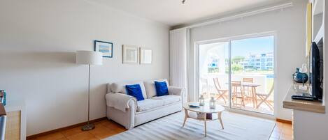 A modern living room with a sofa, a small table, and a view of the outside.