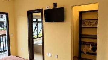 Un dormitorio con cama, televisor y piso de madera.