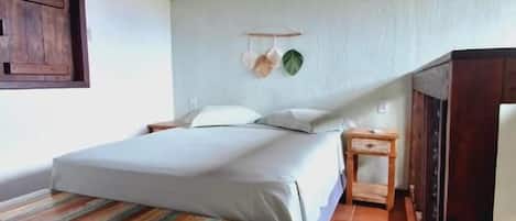 Un dormitorio con cama, mesita de noche y un banco.