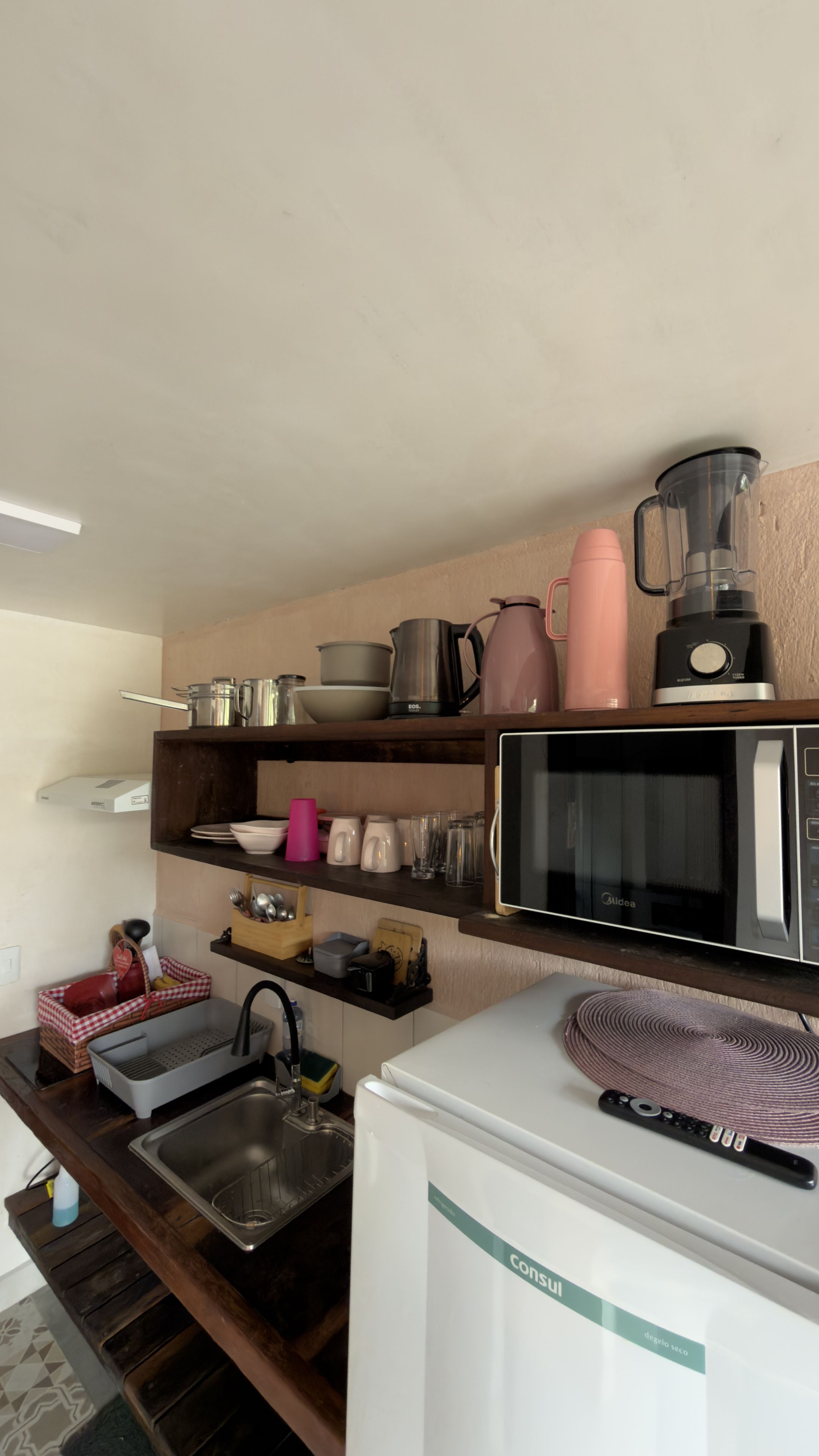Una cocina compacta con microondas, hervidor y cafetera sobre la encimera.