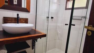 Une salle de bain avec une douche à parois de verre, un meuble-lavabo en bois avec un lavabo blanc et un miroir au-dessus du lavabo.
