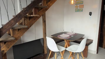 A dining area with a wooden staircase, white chairs, and a table set for two.