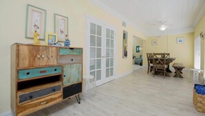 Una habitación con un armario de madera, una mesa de comedor con sillas y una puerta con paneles de vidrio.