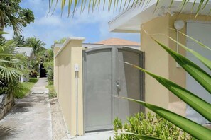 A residential property with a gated entrance, a concrete pathway, and a small garden area.