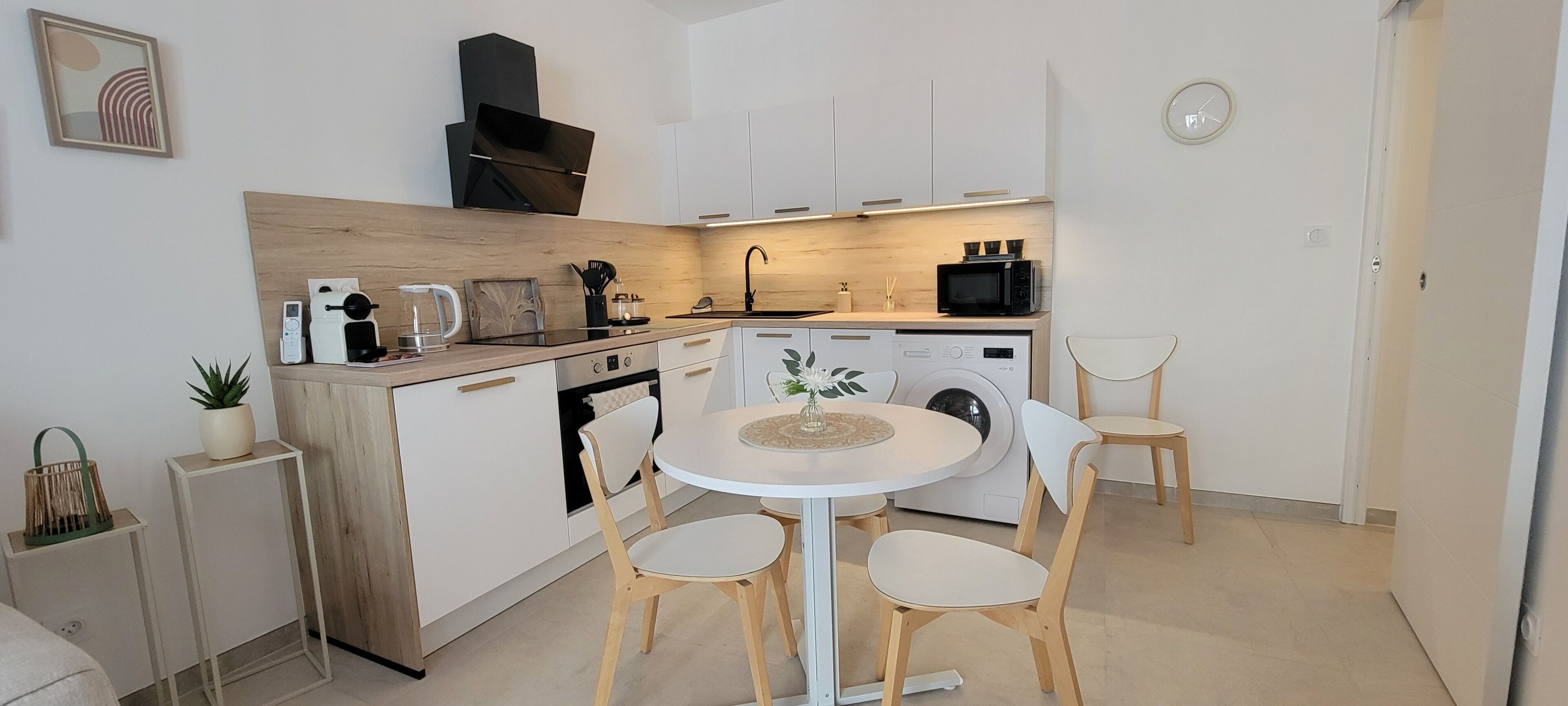 A compact kitchen with a dining area, a washing machine, and a microwave.