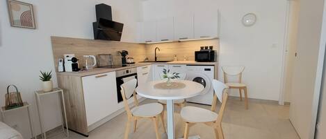 A compact kitchen with a dining area, a washing machine, and a microwave.