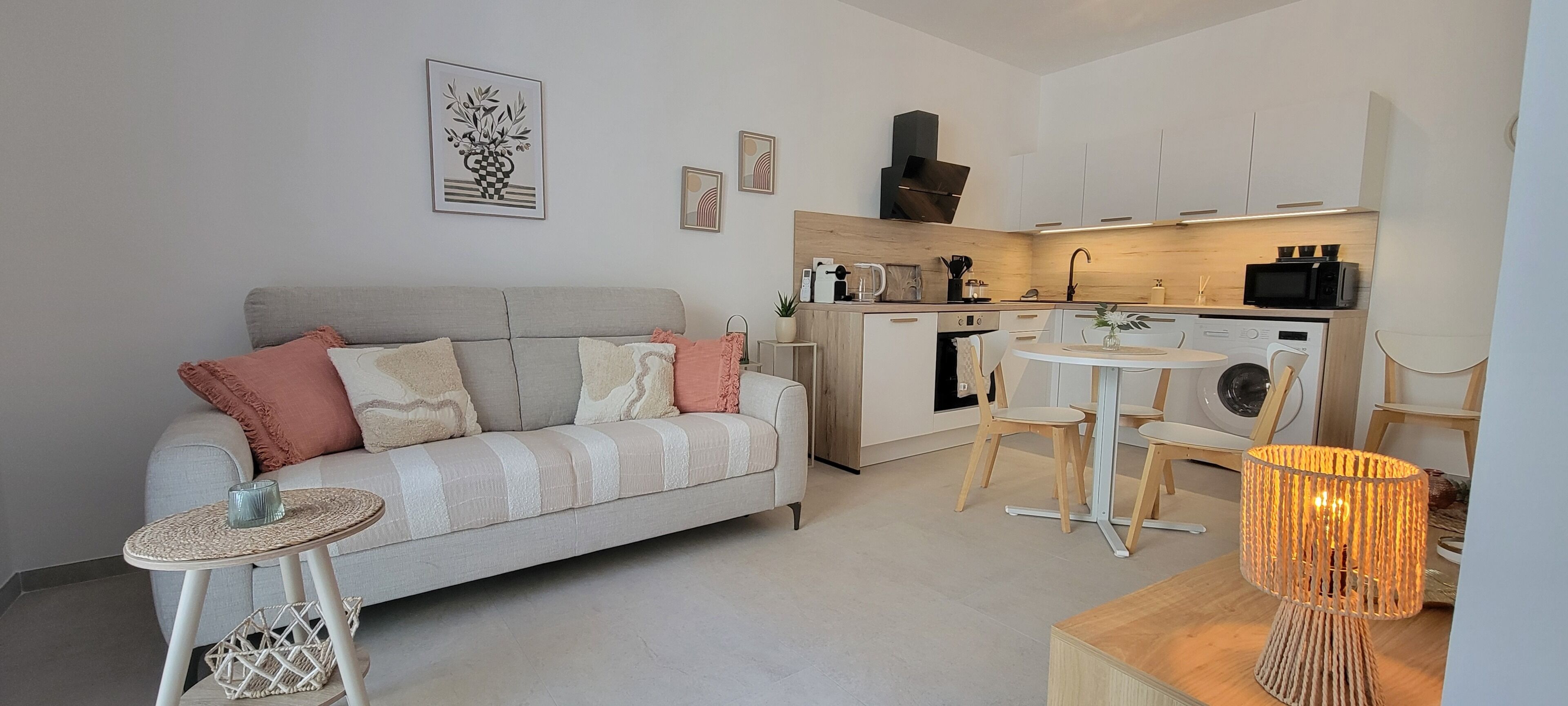 Un espace de vie compact comprenant un canapé, une petite table ronde, un lave-linge, un four à micro-ondes et un coin repas.