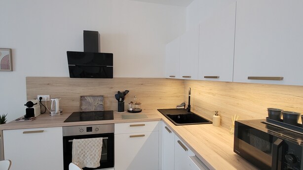 Una cocina moderna con estufa negra, un lavamanos y armarios de madera.