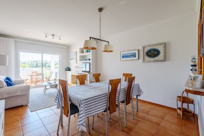 Ein helles Wohnzimmer mit Essbereich, großen Fenstern und Blick ins Freie.