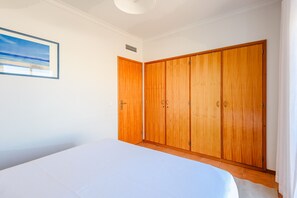 Ein Schlafzimmer mit Bett, Holzschrank und einem Bild an der Wand.