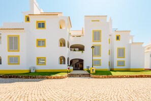A white building with yellow trim and multiple windows, featuring a central entrance with a staircase leading to an upper level. - Casa Monteverde (Loulé)