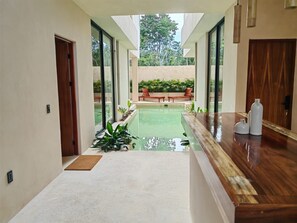 A modern hotel corridor with a pool, wooden furniture, and potted plants. - Koom Tulum, Your Perfect Getaway to Experience the Riviera Maya (Pet-Friendly) (Tulum)