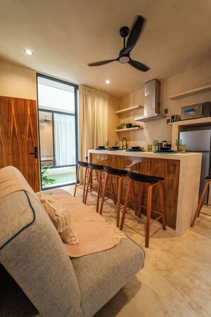A modern kitchen with a central island, bar stools, and a ceiling fan. - Koom Tulum, Your Perfect Getaway to Experience the Riviera Maya (Pet-Friendly) (Tulum)