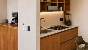 A modern kitchen with wooden cabinets, a built-in stove, and a coffee machine. - Olivo Mío Apartment (La Paz)