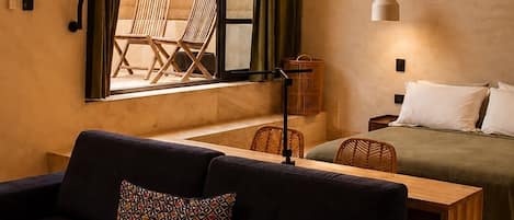A modern room with a dark sofa, a bed, a table, and a ceiling fan.