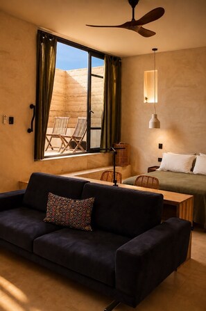 A modern room with a dark sofa, a bed, a table, and a ceiling fan. - Olivo Mío Apartment (La Paz)