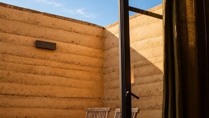 A room with a large sliding glass door, two wooden chairs, a small table, and a potted plant. - Olivo Mío Apartment (La Paz)