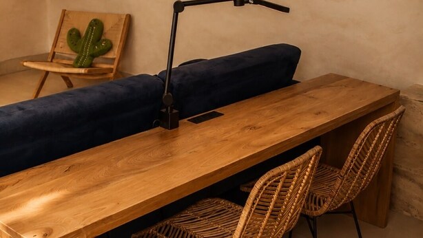 A wooden dining table with two wicker chairs, a blue cushion, and a wall-mounted mirror. - Olivo Mío Apartment (La Paz)