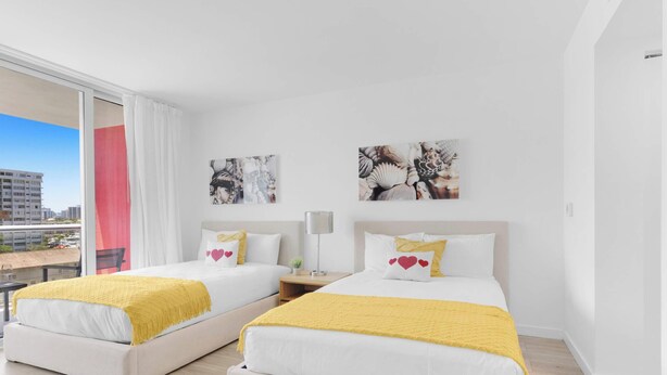 Ein Hotelzimmer mit zwei Betten, einem großen Fenster und Kunstwerken an den Wänden.