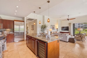 Your spacious gourmet kitchen flows seamlessly into the living area, featuring granite countertops, stainless steel appliances, and warm pendant lighting for memorable meals. - Dive into paradise at Honua Kai - Konea 102 (Lahaina)