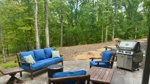 Une terrasse extérieure avec un canapé, des chaises et un barbecue.