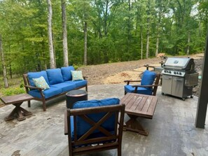 Eine Terrassengruppe mit einer Couch, Stühlen und einem Grill.