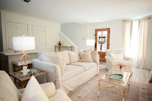A living room with a sofa, armchairs, a coffee table, and a lamp.