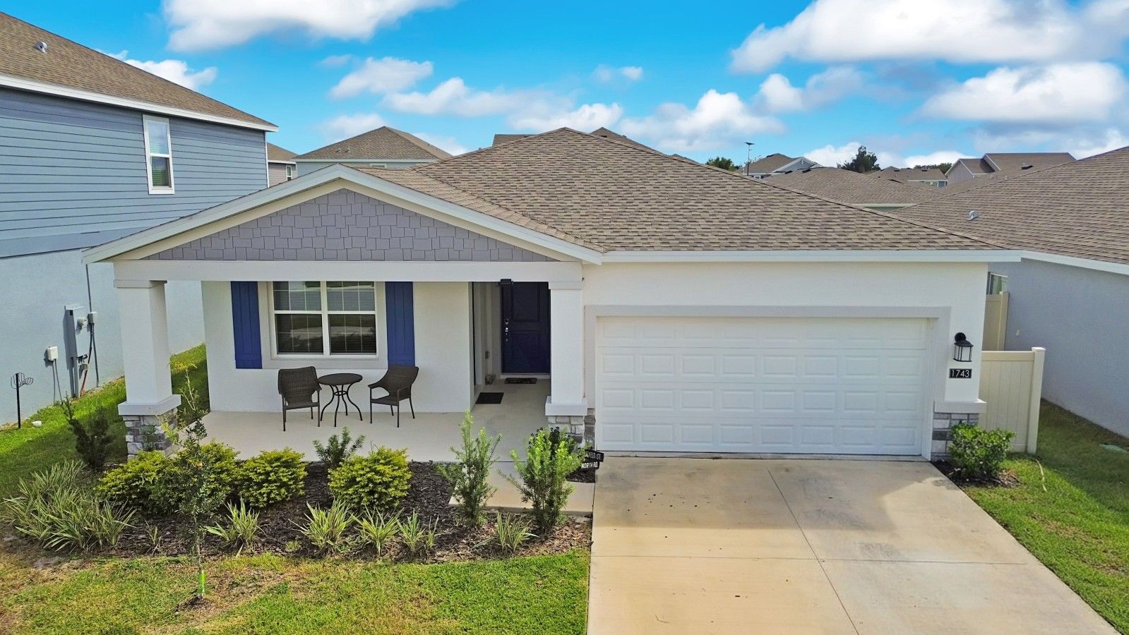 Ein Bungalow mit Garage, überdachter Terrasse und gepflegtem Rasen.