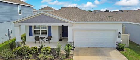 A single-story house with a garage, a covered patio with chairs, and a well-maintained lawn.