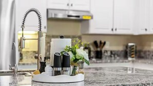 Une cuisine dotée d’un plan de travail en granit, d’un robinet moderne et d’un élément décoratif central agrémenté de bougies et de plantes.