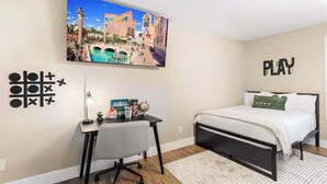Une chambre à coucher comprenant un lit, un bureau et un téléviseur fixé au mur, qui diffuse une vue sur le paysage urbain.