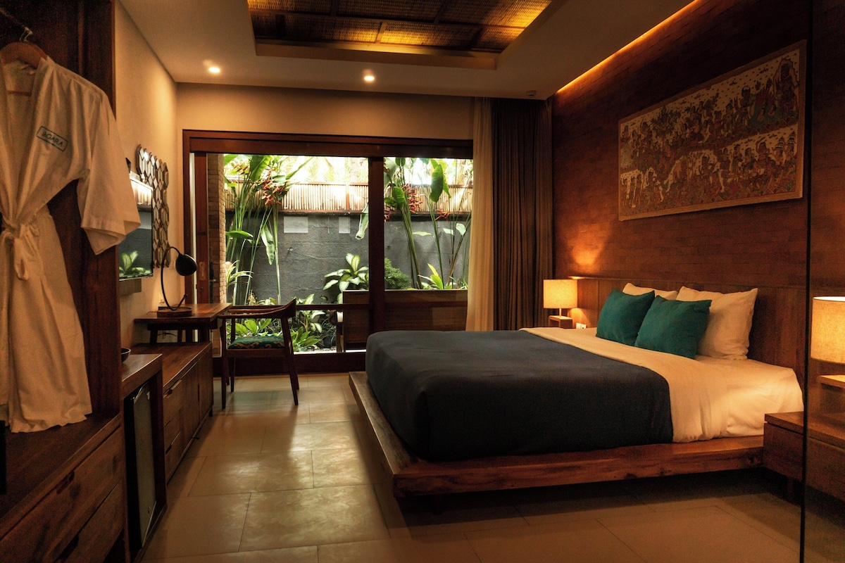A bedroom with a bed, bedside tables, a desk, and a chair.