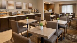 A hotel dining area with multiple tables and chairs, a buffet station with various food items, and a coffee bar. - NovaStar Test Hotel od0mjx (Springfield)