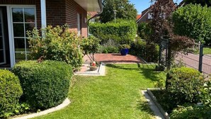 Um imóvel residencial com gramado bem cuidado, fachada de tijolos e antena parabólica.