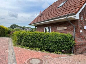 A brick building with a red-tiled roof, a sign indicating it's a 'Forsthaus' (forest house), and a well-maintained hedge in front. - NEW! Achterdeck Vacation Home (Hooksiel)