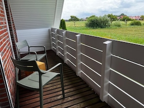 A balcony with a wooden floor, metal chairs, and a white railing. - NEW! Achterdeck Vacation Home (Hooksiel)