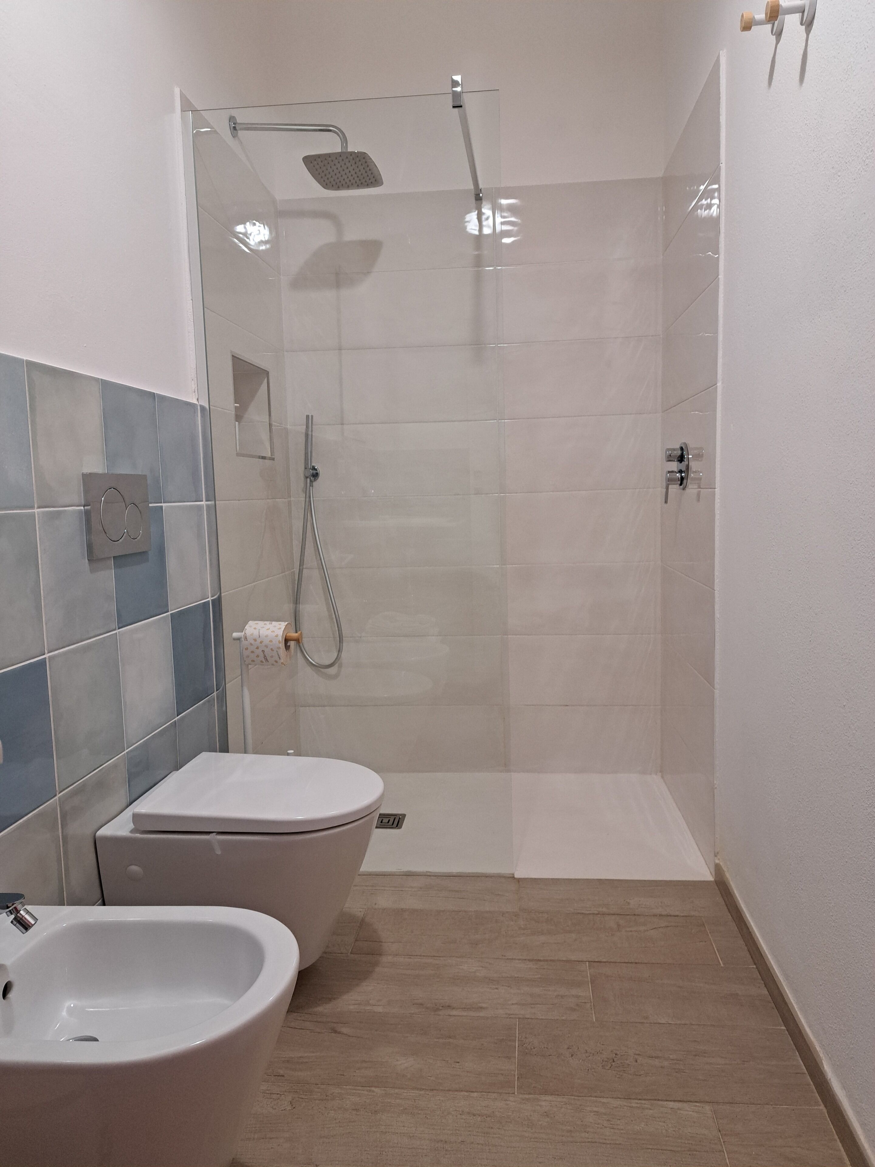 A bathroom with a shower, toilet, and bidet.