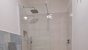 Et badeværelse med bruser, toilet og bidet.