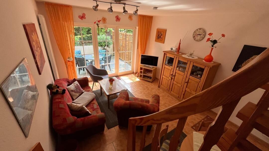 Ein Wohnzimmer mit einer Couch, einem Fernseher, einem Holzschrank und einer Treppe.